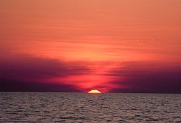 Oben roter Himmel, unten der Ozean mit kleinen Wellen wird vom Himmel erleuchtet.